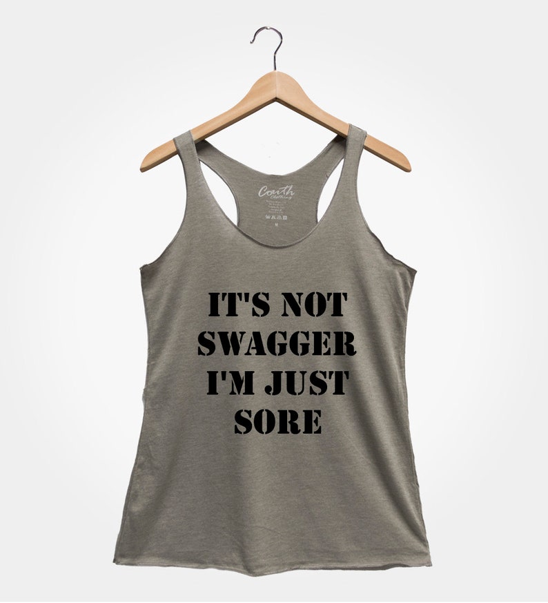 K&ouml;nnte beinhalten: Ein graues Tanktop mit dem Text "IT'S NOT SWAGGER I'M JUST SORE" in Schwarz gedruckt.