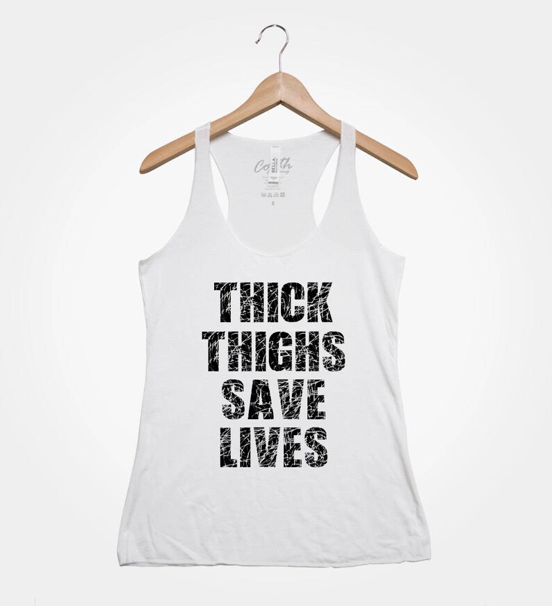 May include: White tank top with a black graphic that says "Thick Thighs Save Lives".