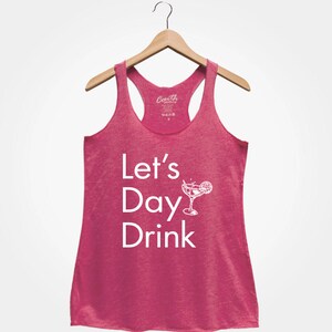 May include: Pink racerback tank top with the text "Let's Day Drink" and a white illustration of a margarita glass with a lime wedge.