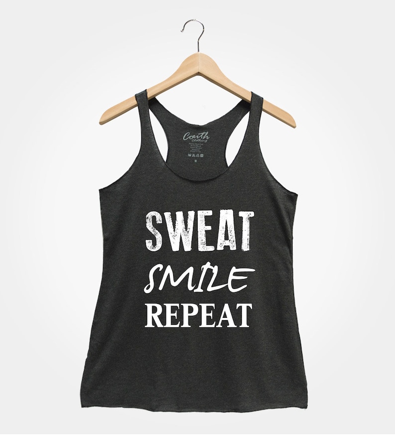 May include: A dark gray tank top with the text "SWEAT SMILE REPEAT" in white. The text has a distressed, vintage look.
