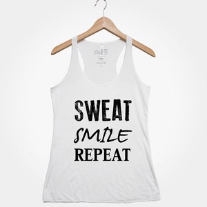 May include: White tank top with black text that reads "Sweat Smile Repeat".