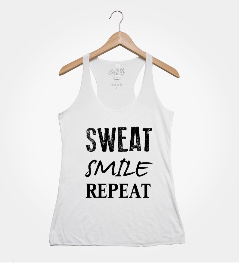 May include: White tank top with black text that reads "Sweat Smile Repeat".