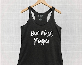 Puede incluir: Camiseta de tirantes negra con el texto "But First, Yoga" en pintura blanca.
