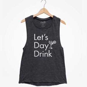 May include: A dark gray sleeveless shirt with the text "Let's Day Drink" in white lettering. A white outline of a cocktail glass with a lime wedge is next to the text.