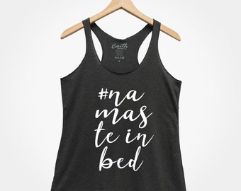 Puede incluir: Un top de tirantes gris oscuro con el texto "#na mas te in bed" en letras blancas.