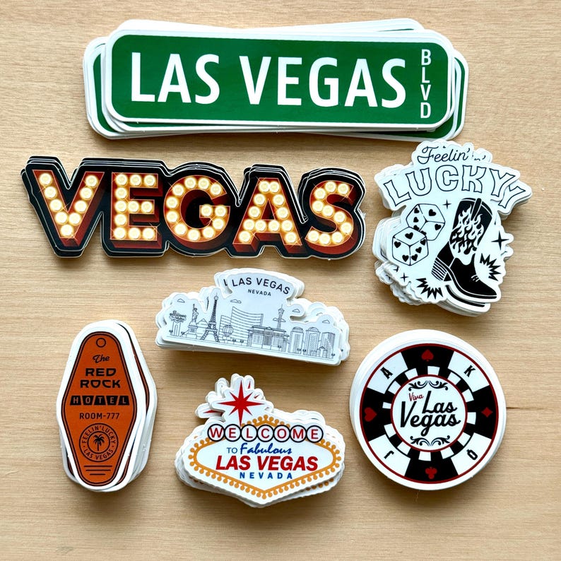May include: A collection of Las Vegas-themed stickers. Includes a green street sign, a marquee-style "VEGAS" sign, a "Feelin' Lucky" sticker with dice and a cowboy boot, and a hotel key tag. Other stickers feature the Las Vegas skyline and a casino chip.