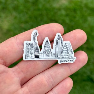 May include: A white sticker featuring a black and white illustration of the Austin, Texas skyline. The sticker includes the text "Austin Texas" at the bottom. The design depicts various buildings and landmarks.