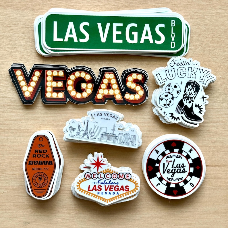 May include: A collection of Las Vegas-themed stickers. Includes a green street sign, a marquee-style "VEGAS" sign, a "Feelin' Lucky" sticker with dice and a cowboy boot, and a hotel key tag. Other stickers feature the Las Vegas skyline and a casino chip.