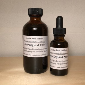 May include: Two brown glass bottles of herbal extract. The larger bottle has a black cap, and the smaller bottle has a dropper. Both bottles have white labels with black text that reads "New England Aster" and "Linden Tree Herbals".