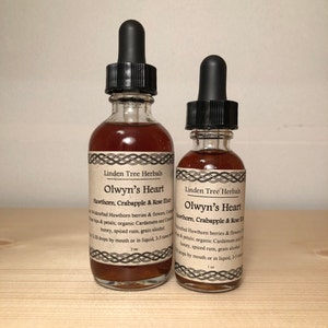 May include: Two glass bottles with dropper tops filled with a dark red liquid. The bottles are labeled "Olwyn's Heart Hawthorn, Crabapple & Rose Elixir" and are made by Linden Tree Herbals. The larger bottle is 2 oz and the smaller bottle is 1 oz.