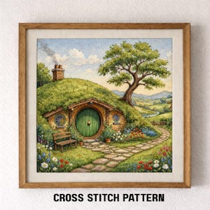 May include: A framed cross-stitch pattern depicts a whimsical hobbit hole nestled in a grassy hill. The scene includes a green door, stone path, bench, and a large tree. Colorful flowers and a winding path lead to a distant landscape under a blue sky.