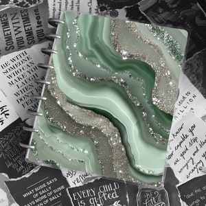 Może przedstawiać: Zielony notes z marmurowym wzorem i spiralnym oprawą. Na okładce znajduje się cytat: "Każde dziecko jest obdarowane talentem. Po prostu rozpakowują swoje prezenty w różnych momentach."