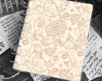 May include: A cream-colored notebook with a pink floral pattern. The notebook has a clear cover and a ring binding. The text "Every child is gifted. They just unwrap their packages at different times." is visible on the cover.