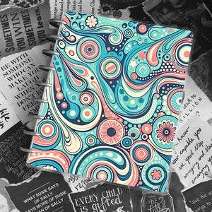 May include: A spiral-bound notebook with a colorful, abstract design. The cover features a pattern of swirling shapes in shades of blue, teal, pink, and cream. The notebook is surrounded by torn pieces of paper with inspirational quotes.