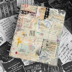 May include: A spiral-bound journal with a collage-style cover. The cover features layered paper elements, including ledger pages, stamps, and handwritten notes. The background is a mix of black and white torn paper with inspirational quotes.