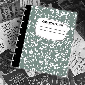 May include: A composition notebook with a green cover and white splotches. The notebook has a blank label with the word "COMPOSITION" printed above it. The notebook is surrounded by various pieces of paper with inspirational quotes and sayings.
