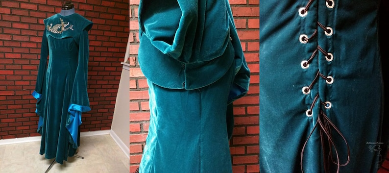 May include: A teal velvet gown with long sleeves and a hood, displayed on a mannequin. The dress features a high collar with embroidered detailing and flared sleeves with blue satin cuffs. The back of the dress has a corset-style lace-up closure.