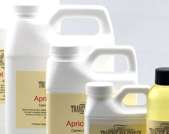 May include: Five bottles of apricot kernel oil in various sizes, ranging from a small 2 oz bottle to a large 1 gallon jug. The bottles are all white with black labels and the text "Traverse Bay Soap Co." and "Apricot Kernel Oil" is printed on the labels.