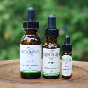 May include: Three amber glass bottles with dropper tops containing pine essential oil. The bottles are labeled "Traverse Bay Soap Co. Pine 100% Pure Essential Oil 1/2 oz."