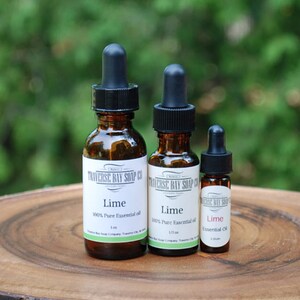May include: Three amber glass bottles with black droppers containing lime essential oil. The bottles are labeled "Lime" and "100% Pure Essential Oil". The bottles are on a wooden slice.