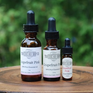 May include: Three amber glass bottles with dropper tops containing 100% pure grapefruit pink essential oil. The bottles are labeled "Traverse Bay Soap Co."