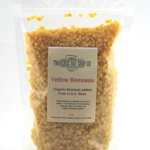 以下が含まれることがあります： 黄色い蜜蝋ペレットが入った透明なビニール袋。袋には「Yellow Beeswax」と「Organic Beeswax pellets From U.S.A. Bees」と書かれたラベルが付いています。袋には454グラムの蜜蝋が入っています。