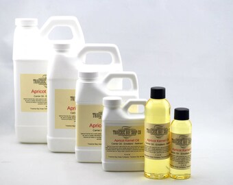 May include: Various sizes of white plastic bottles and clear glass bottles filled with a yellow liquid. The bottles have labels that read "Apricot Kernel Oil" and "Traverse Bay Soap Co."