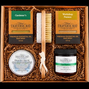 May include: A gift set containing two 5.5 oz bars of Traverse Bay soap labeled Gardener's and Workshop Pumice, a wooden nail brush with a pumice stone, a 2 oz tin of Healing Salve, and a 4 oz jar of Skin Therapy hand and body lotion.