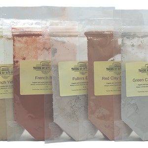 May include: Five clear plastic pouches filled with different colored clays. The pouches are labeled with the names of the clays: French Yellow, French Red, Fullers Earth, Red Clay, and Green Clay (France). The labels also include the brand name and product information.