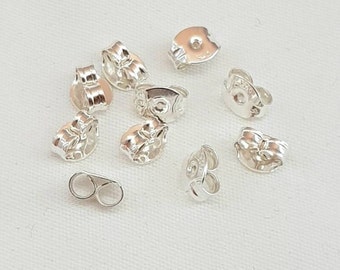 May include: A set of silver earring backs, some with a decorative design, and some with a simple loop design.