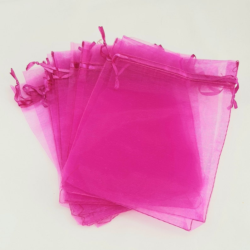 May include: A stack of pink organza gift bags with drawstrings. The bags are made of sheer fabric and are perfect for small gifts or favors.