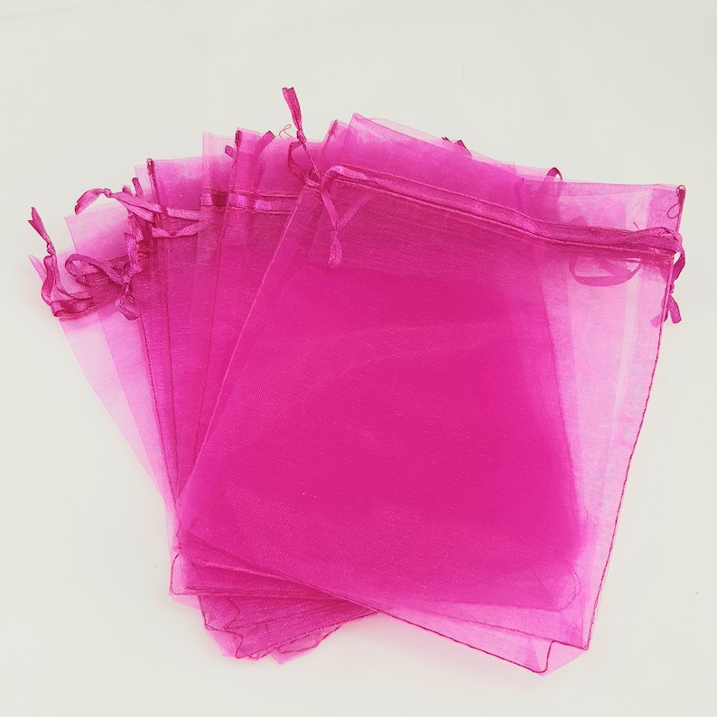 May include: A stack of pink organza gift bags with drawstrings. The bags are made of sheer fabric and are perfect for small gifts or favors.