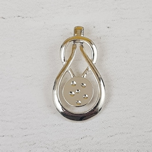 May include: A silver pendant with a distinctive design. It has a teardrop shape with a circular centre, decorated with small, raised dots. The top has a loop for a chain. The pendant is likely made of metal.