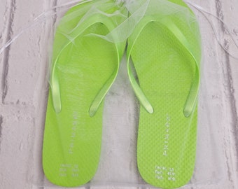 May include: A pair of lime green flip flops with the word "PRIMARK" printed on the straps. The flip flops are in a white mesh bag. The size is printed on the bottom of the flip flops: UK/IRL 7/8 EUR 41/42 USA 8/9.