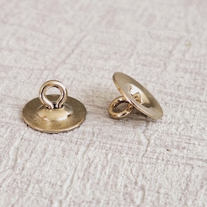 May include: Two gold-toned metal buttons with a loop on top. The buttons are round and have a slightly raised center.