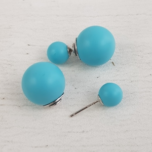 May include: Three pairs of turquoise blue double-sided stud earrings. The earrings are round and have a smooth finish.