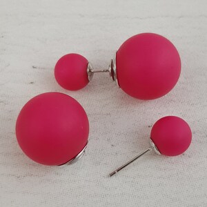 May include: A pair of pink double-sided stud earrings. The earrings have a silver post and a round, pink ball on each side.