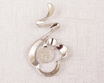 Puede incluir: Pendiente de metal plateado con un diseño de espiral y una forma de flor con un centro texturizado.