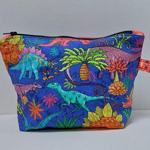 Children&#39;s toiletry bag in designer fabric with dinosaurs on a blue background