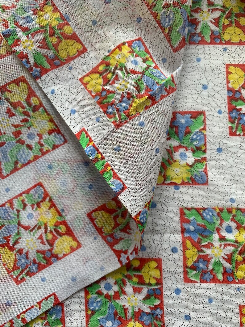 May include: White fabric with a repeating pattern of red, yellow, blue, and green floral squares. The fabric has a subtle dotted texture.