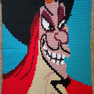 May include: Crocheted portrait of Captain Hook from the Disney movie Peter Pan. The image is made with red, black, white, beige, and blue yarn.