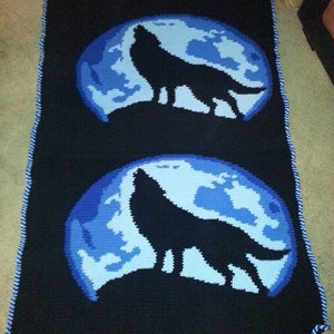 Puede incluir: Una manta de crochet negra y azul con dos lobos en silueta aullando a la luna.