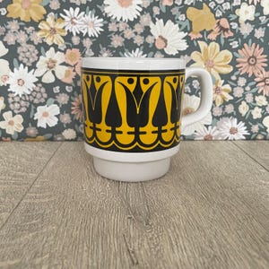 Könnte beinhalten: Ein Set aus drei Keramikbechern mit gesprenkelter, matter Oberfläche. Die Becher sind in den Farbtönen Creme, Hellgrau und Dunkelgrau gehalten. Jeder Becher hat ein schlichtes, minimalistisches Design und einen abgerundeten Griff.