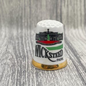 May include: A white ceramic mug with a black handle and the text "But First, Coffee" in a black, handwritten-style font. The mug is on a white surface.