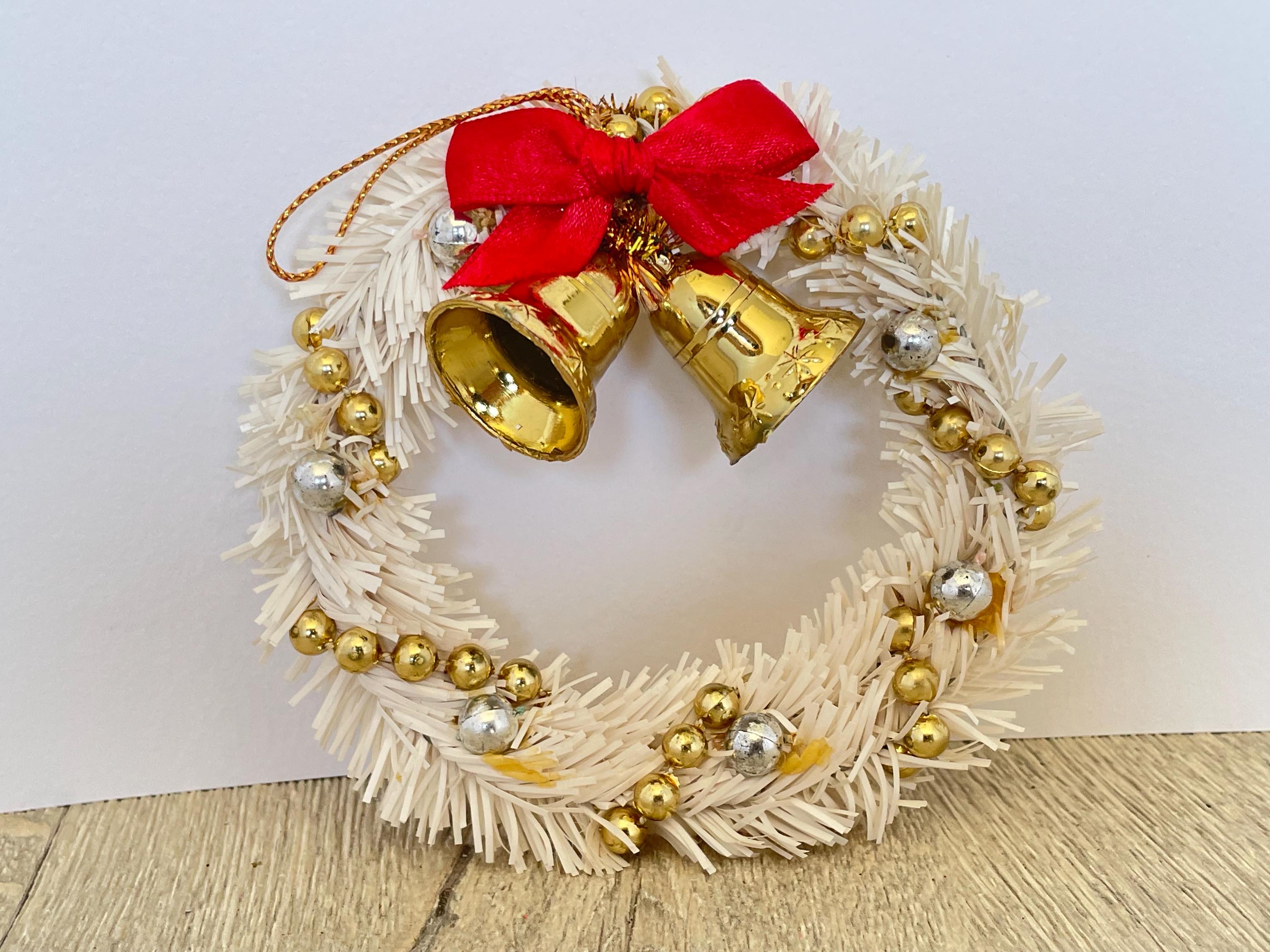 金色のベルと赤いリボンが付いた白いミニティンセルクリスマスリース