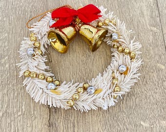 金色のベルと赤いリボンが付いた白いミニティンセルクリスマスリース