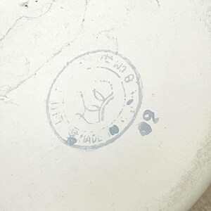 May include: A white ceramic stamp with a circular design featuring a stylised plant and the text "MADE IN ITALY" and "W18".