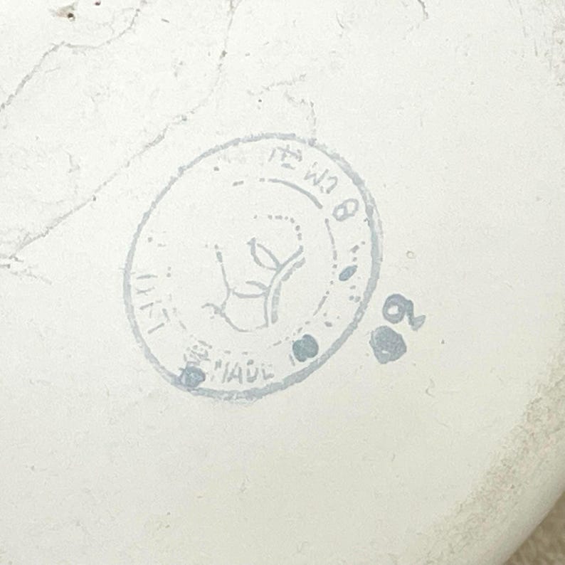May include: A white ceramic stamp with a circular design featuring a stylised plant and the text "MADE IN ITALY" and "W18".
