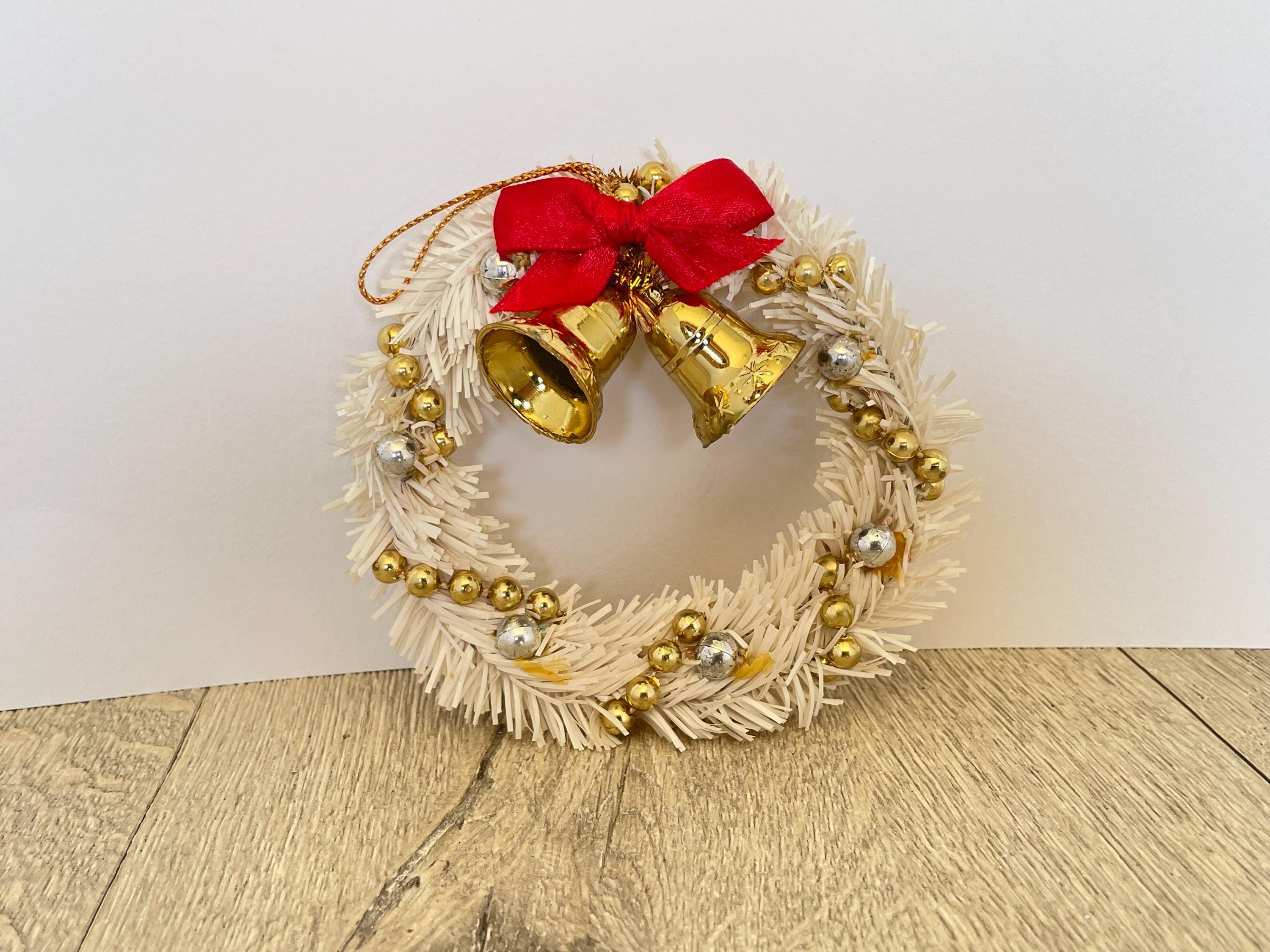 金色のベルと赤いリボンが付いた白いミニティンセルクリスマスリース