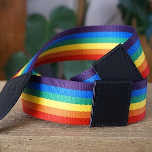 Peut inclure: Sangle de caméra rayée arc-en-ciel avec des accents en cuir noir. La sangle est en tissu tissé et présente un motif arc-en-ciel de rouge, orange, jaune, vert, bleu, indigo et violet.
